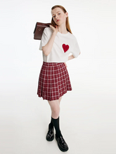 a lady in red plaid tennis skirt with white T-shirt with black loafers